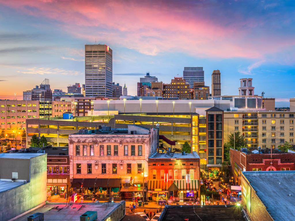 Memphis, Tennessee, USA showing the downtown skyline in the background and a popular strip in the foreground at early evening.
