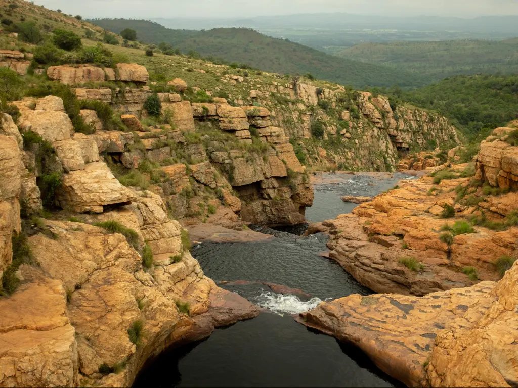 A flowing waterfall carved in a red sandstone valley at the Kgaswane Reserve in South Africa