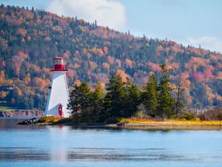 Scenic lighthouse by the water with an autumnal forest in the background