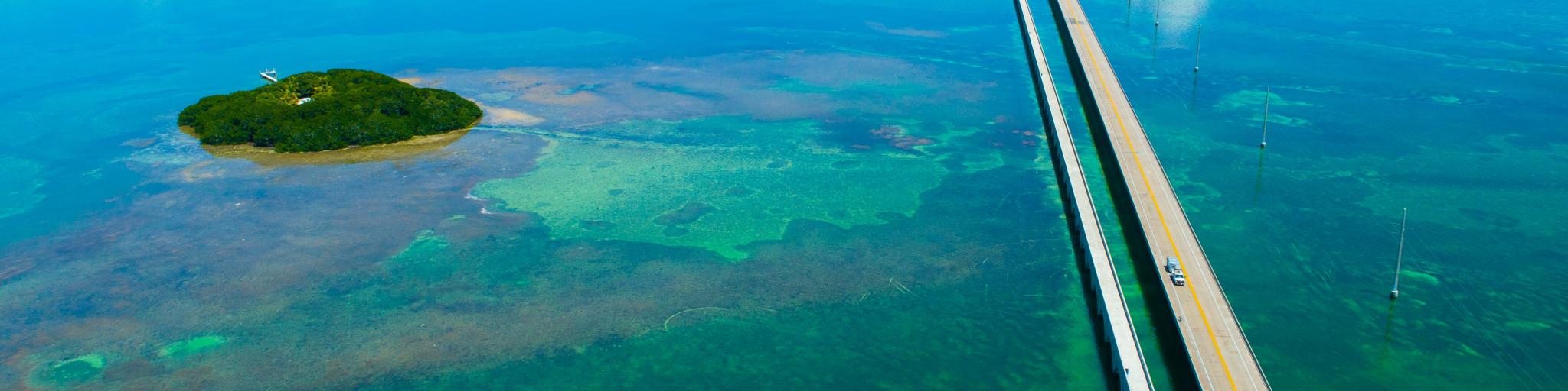 An aerial view of the straight 7 Seven Miles bridge on the Overseas Highway, Florida, with blue waters and reefs visible below the water