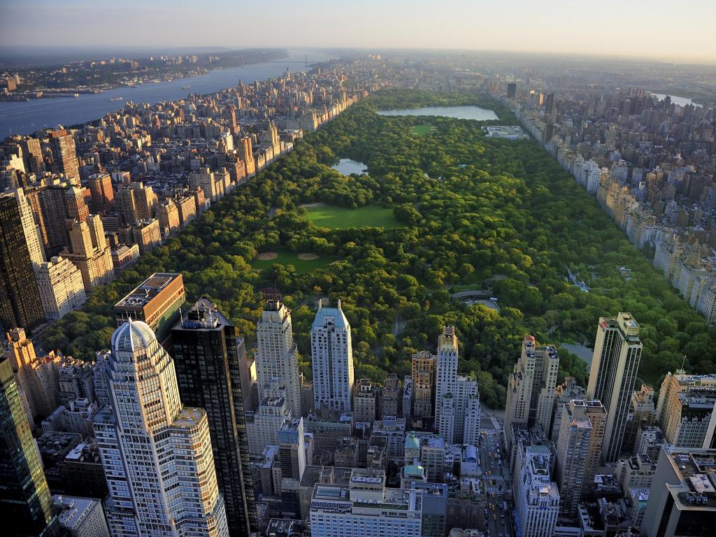Manhattan, New York, USA with an aerial view of Central Park surrounded by skyscrapers on a sunny day.