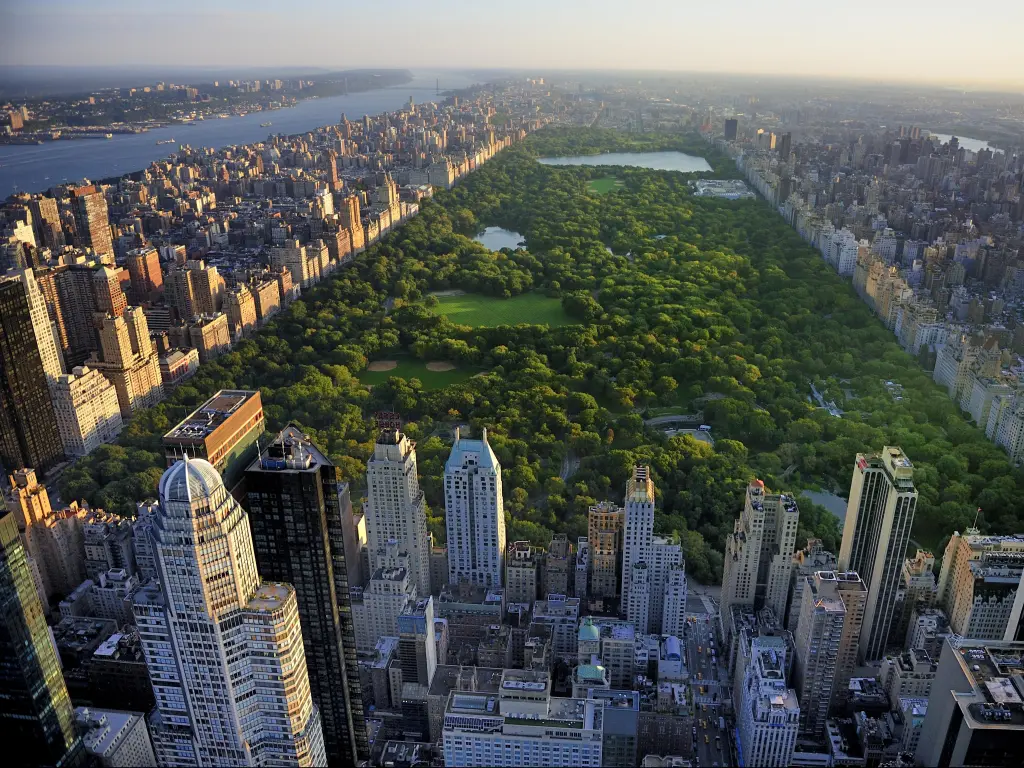 Manhattan, New York, USA with an aerial view of Central Park surrounded by skyscrapers on a sunny day.