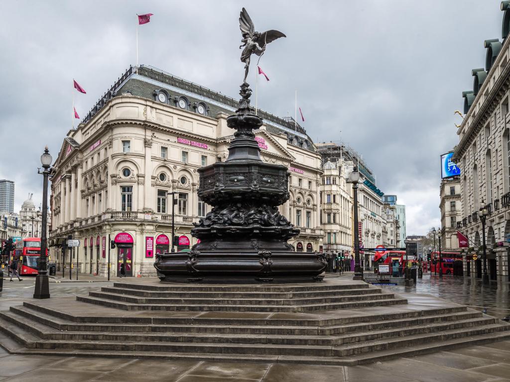 An empty Picadilly Circus with the Shaftesbury Memorial Fountain in the middle on an overcast day.