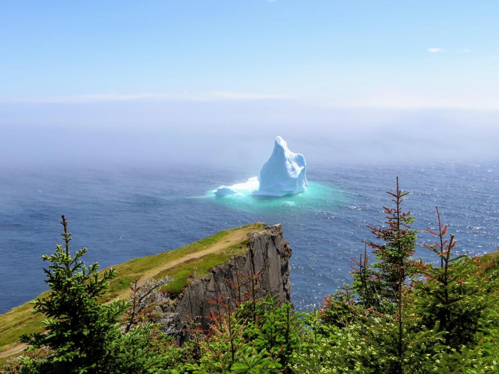 Incredible iceberg floating along the rugged coast beside the Skerwink Trail in Newfoundland and Labrador, Canada.