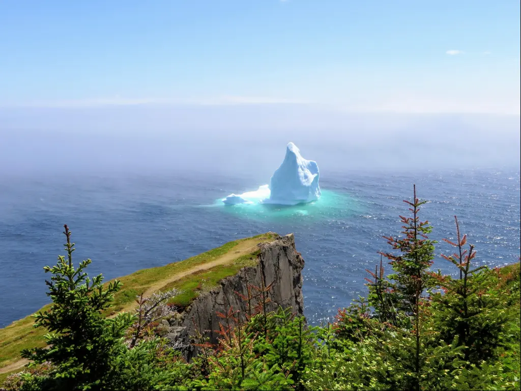 Incredible iceberg floating along the rugged coast beside the Skerwink Trail in Newfoundland and Labrador, Canada.