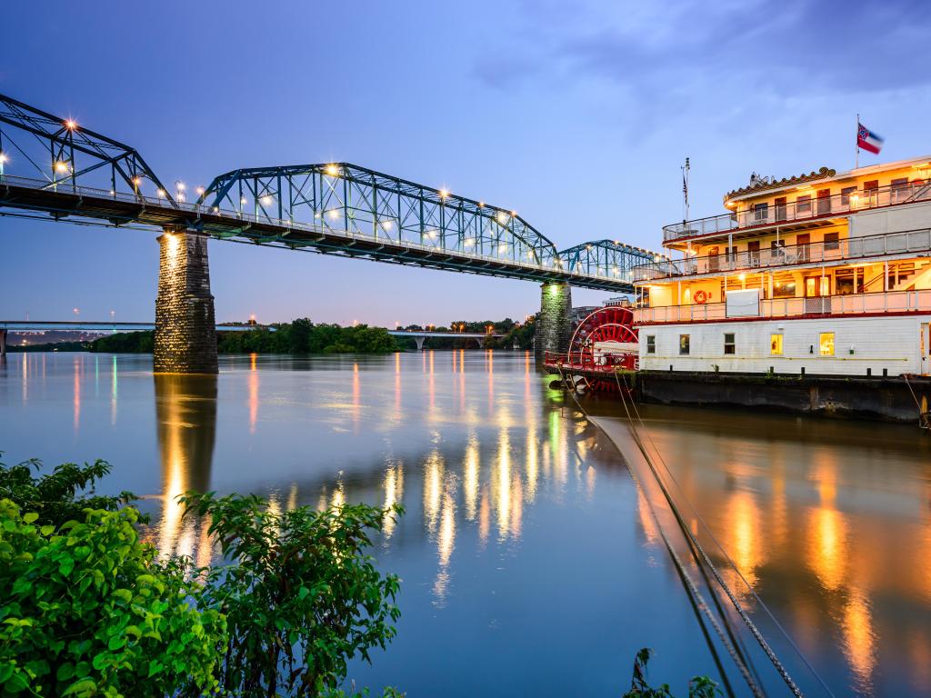 Chattanooga, Tennessee, USA riverfront at early evening with a boat in the foreground and bridge in the distance. 