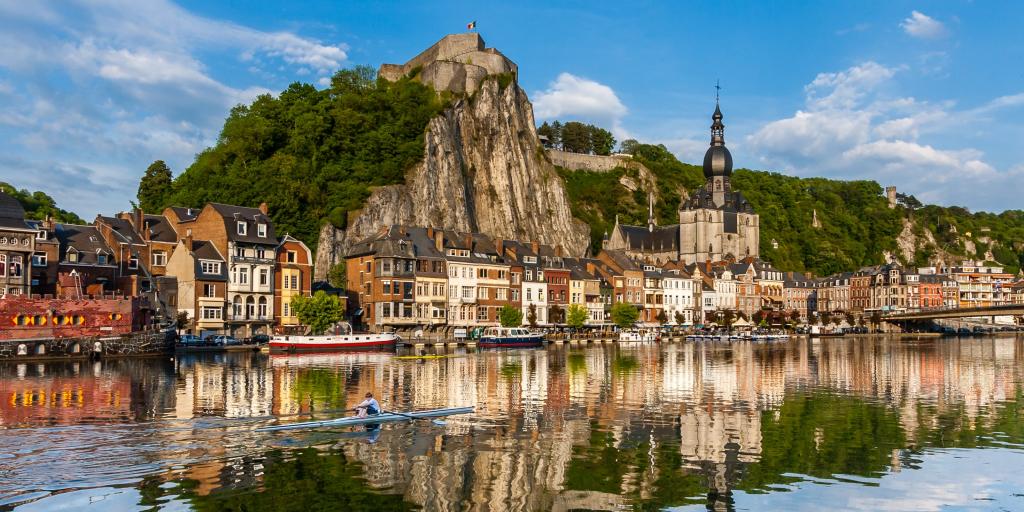 Houses and a church along the waterfront at Dinant, Belgium, with a person kayaking in the water