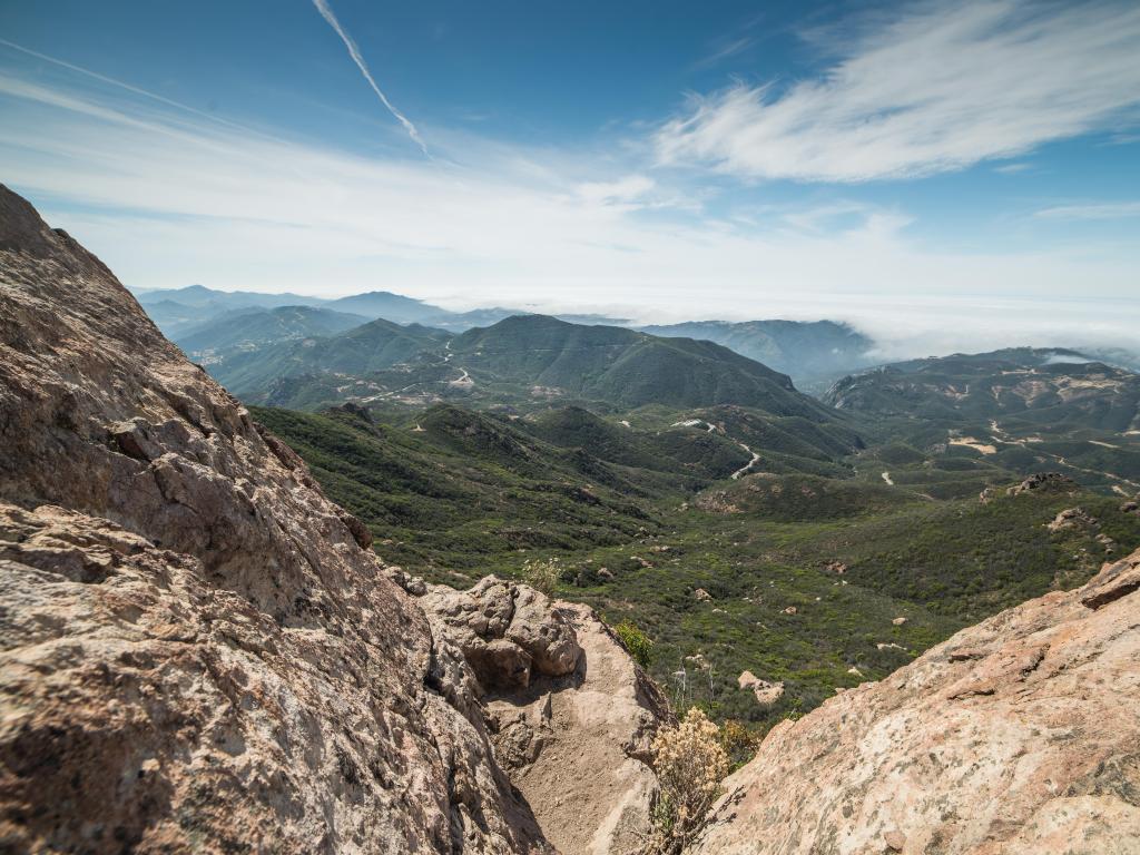 Santa Monica Mountains National Recreation, California with a view from the summit of Sand Stone Peak and green hills in the distance with a foggy horizon. 
