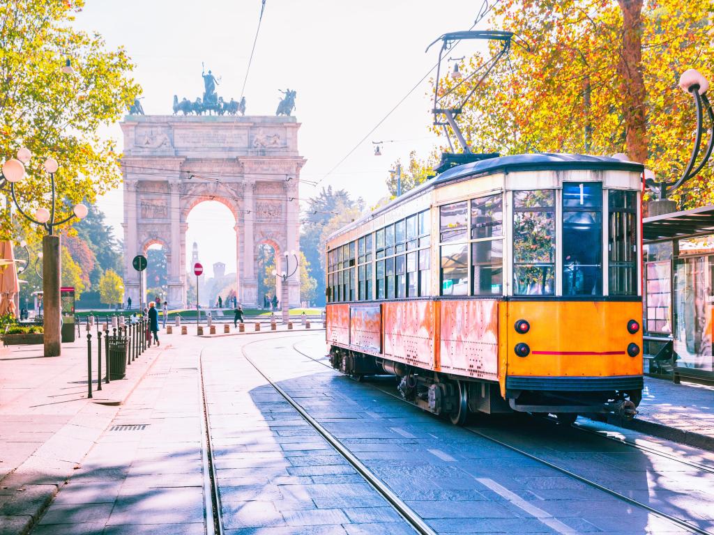 Famous vintage tram in the centre of the Old Town of Milan in the sunny day, Lombardia, Italy. Arch of Peace, or Arco della Pace on the background.