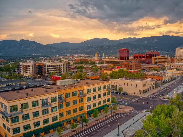 Colorado Springs, Colorado, USA with an aerial view of the city at dusk with the mountains in the distance. 