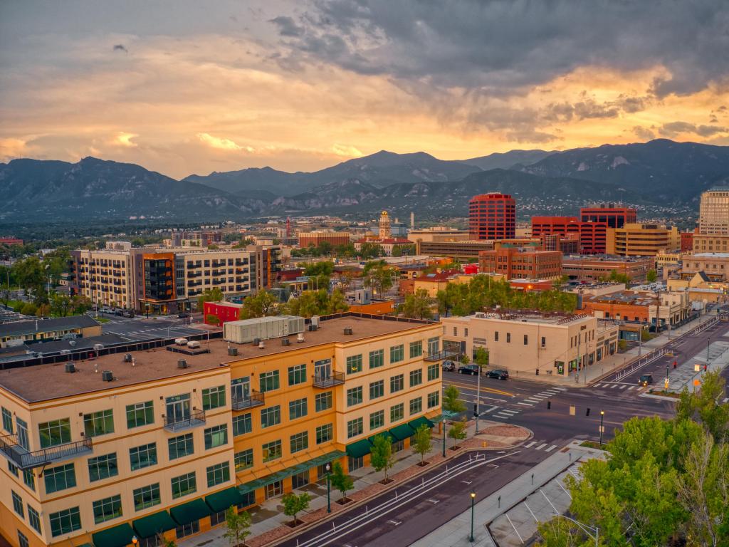 Colorado Springs, Colorado, USA with an aerial view of the city at dusk with the mountains in the distance. 