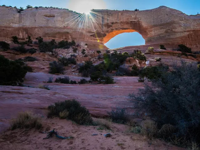 Sun shines through the gap of Wilson Arch in southwest Utah in the early evening