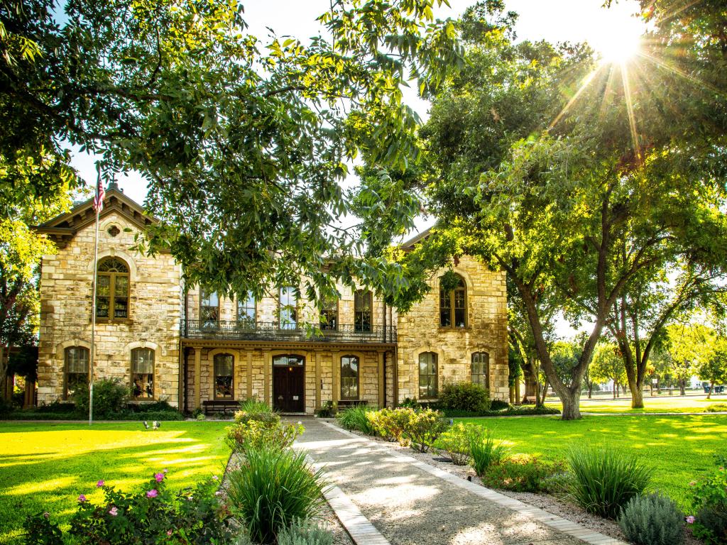 Beautiful Pioneer Memorial Library in Fredericksburg, Texas, situated in a green garden, surrounded by trees on a sunny day