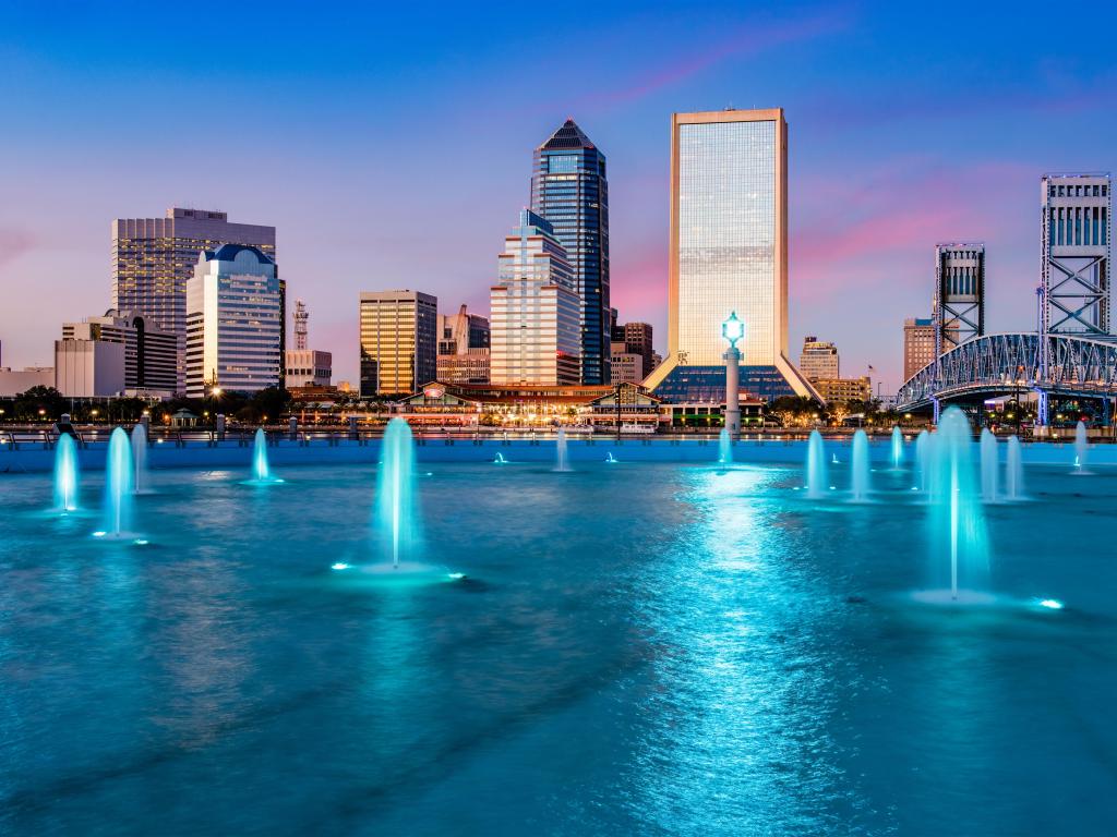 Jacksonville, Florida, USA wit the city skyline in the background and the fountain lit up at night in the foreground.