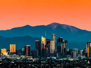 Panoramic view of Los Angeles skyline with mountains in the background and vibrant orange sunset