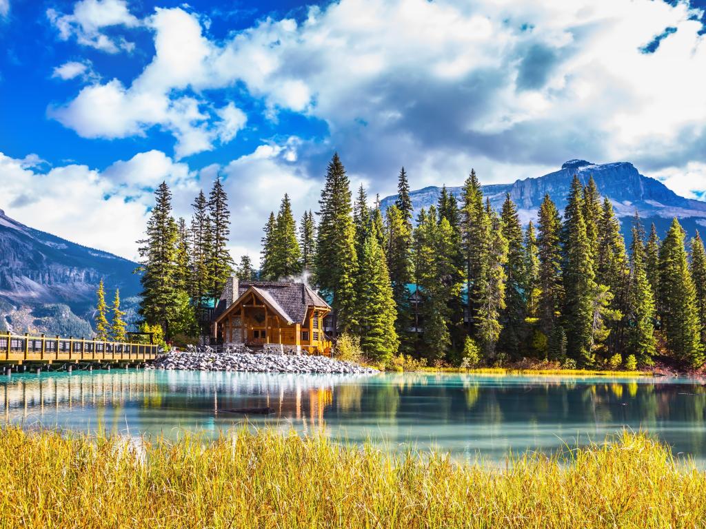 Yoho National Park, Canada with a bridge over Emerald Lake, a coniferous forest and mountains in the background on a sunny day.