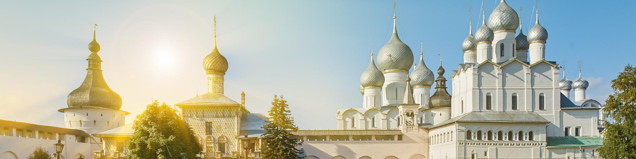 Sunlight streaming onto the white Assumption Cathedral and church of the Resurrection in Rostov Kremlin.