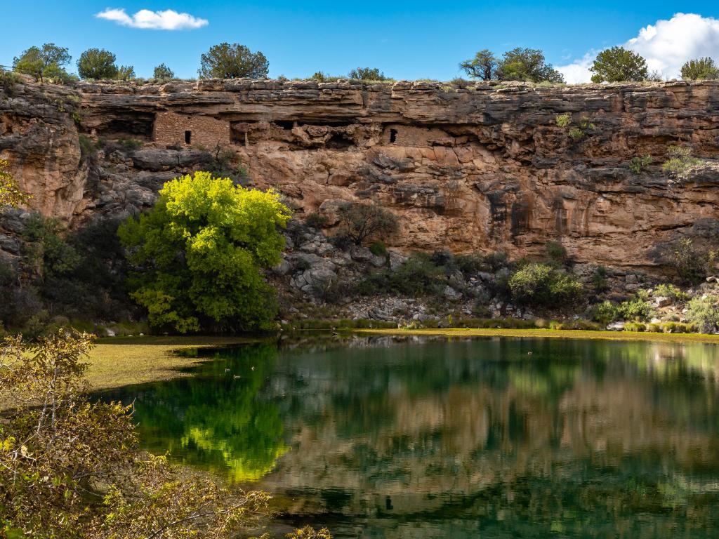 Montezuma Castle National Monument, Arizona, USA with ancient ruins in the background reflecting in the quiet water of Montezuma Well in the foreground.