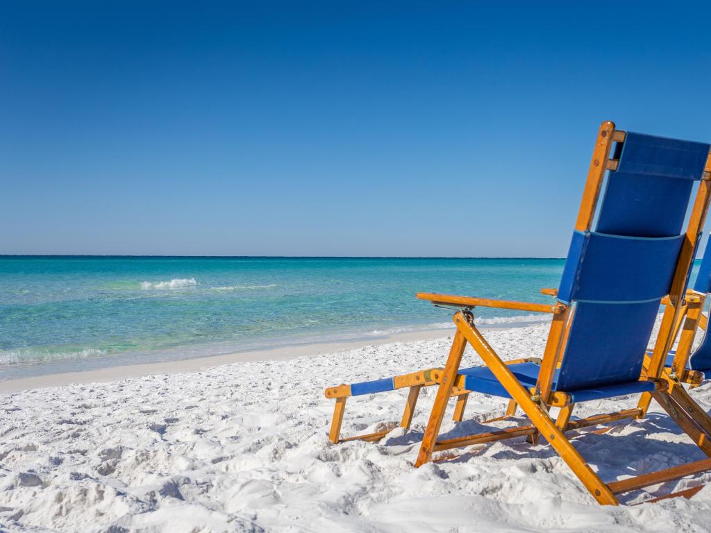 Destin, Florida, USA with beach chairs resting on the beach against a blue sky.