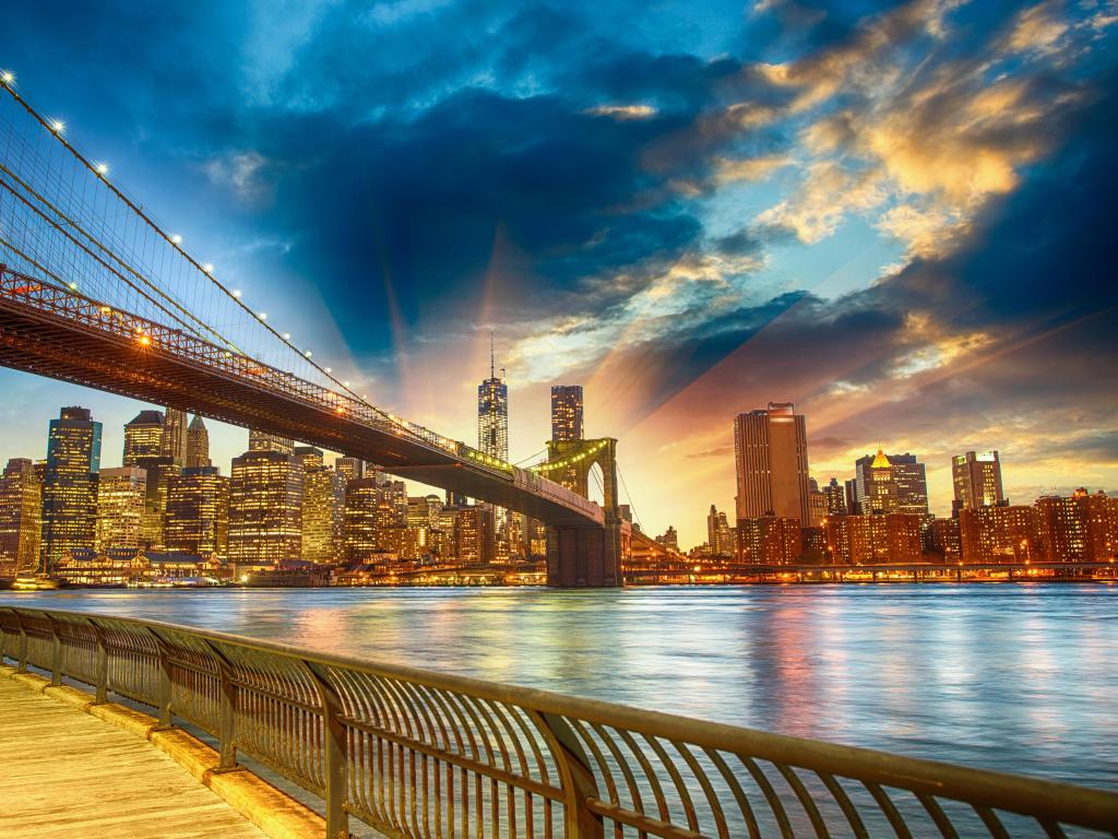 View of Manhattan Skyline and bridge from across river, with vivid sunlight shining behind the buildings