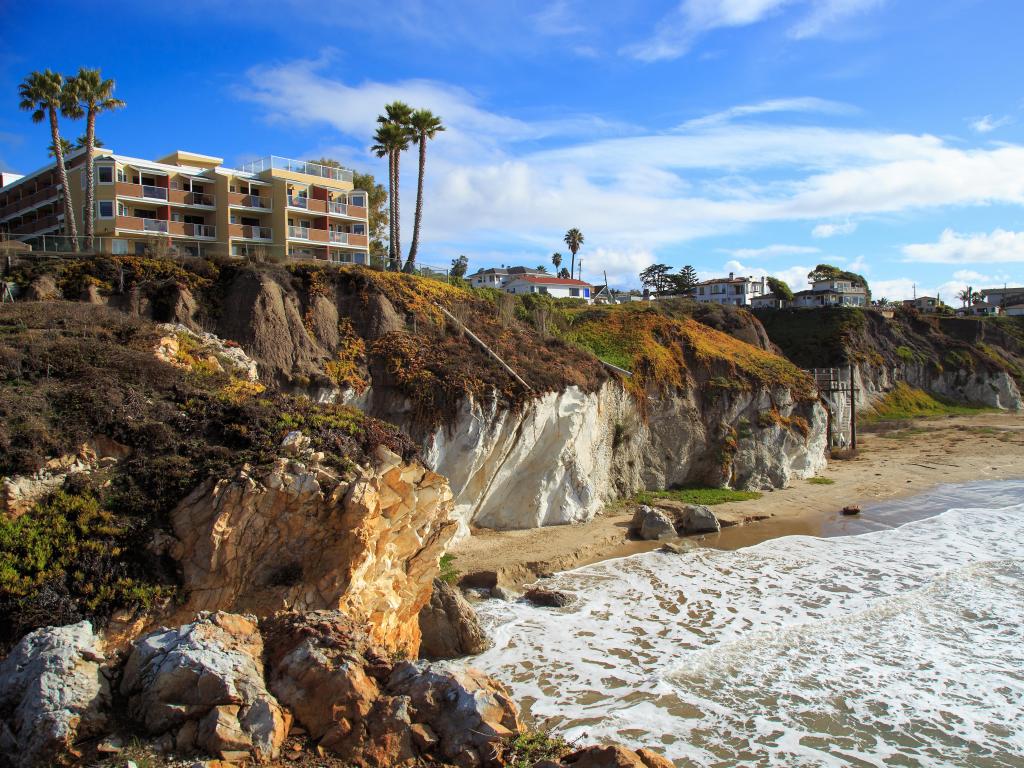 Pismo Beach, California, USA on a sunny afternoon with buildings above the cliffs along the beach.
