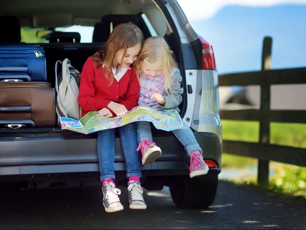 Kids looking at a map to find secret places along the road trip route.