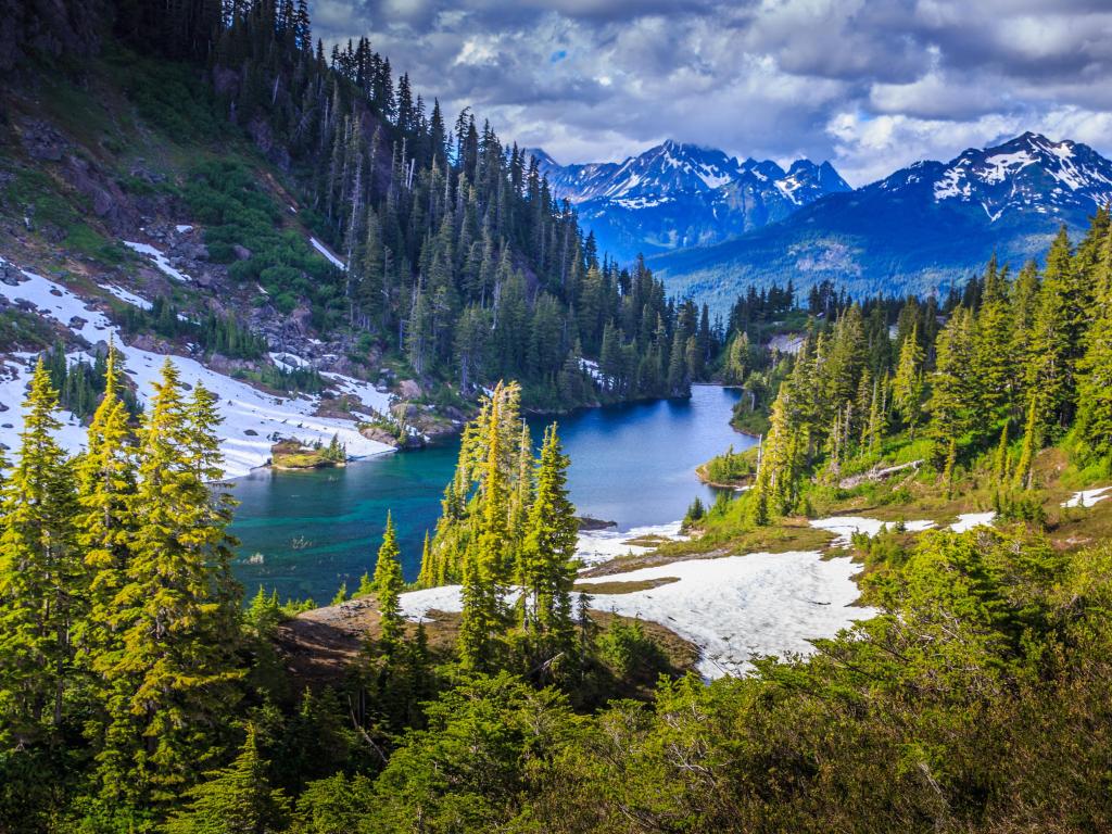 Glacier National Park, Montana, USA with trees and land covered in snow in the foreground looking down to a lake and mountains beyond covered in snow.