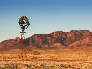 Lone Windmill with the red backdrop of the Outback on a sunny day in Flinders Ranges