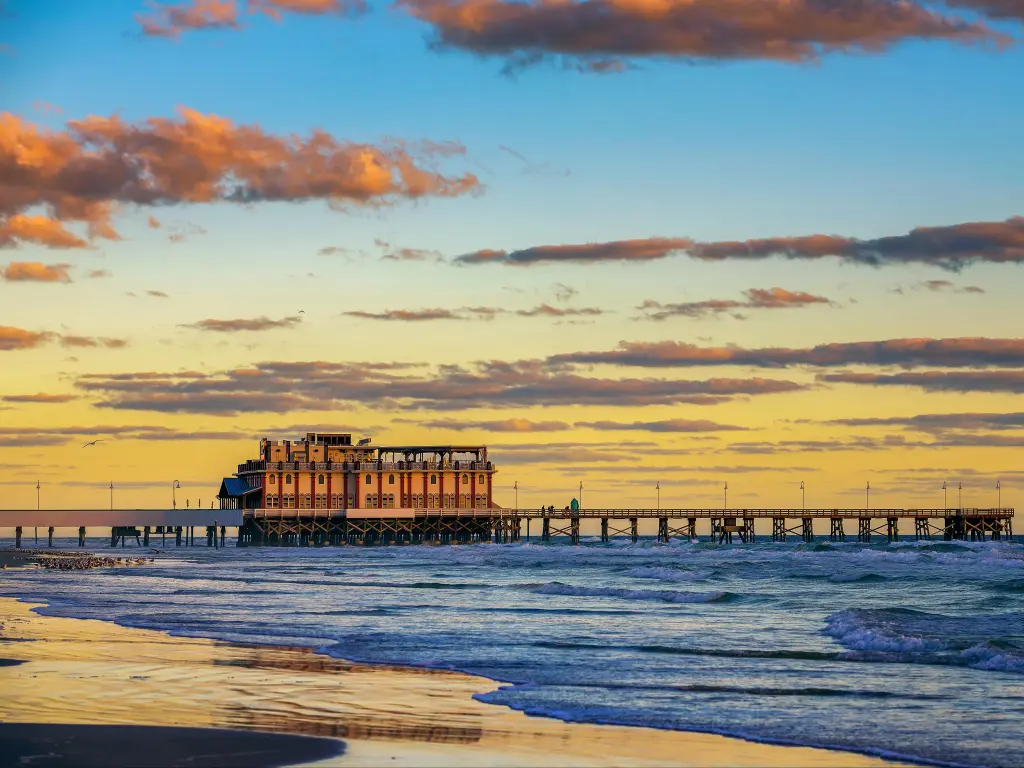 View of Daytona Beach Main Street Pier surrounded by sunset skies and empty blue waters