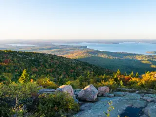 Cadillac Mountain, Acadia National Park, Maine, USA taken as a panoramic shot on a clear sunny day with trees and the lake in the distance.
