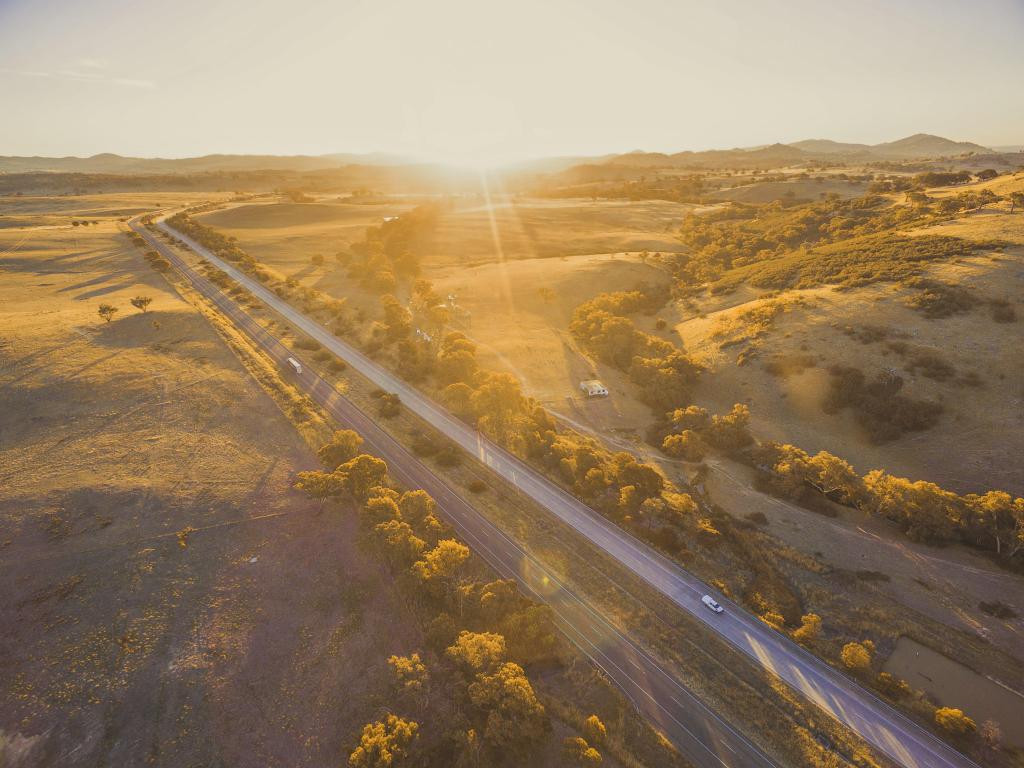 Highway passing through open countryside with bright sunset light illuminating the ground
