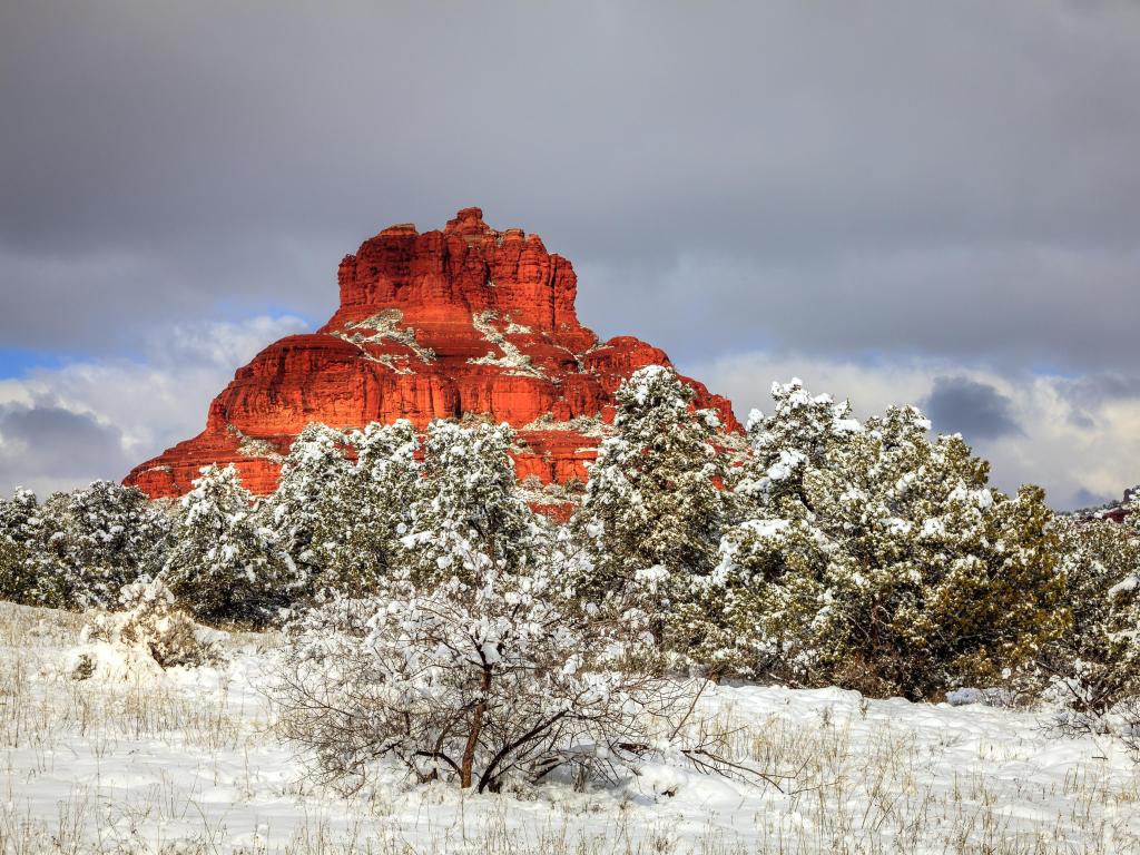 Famous red rock formation under a dusting of snow, overcast grey skies