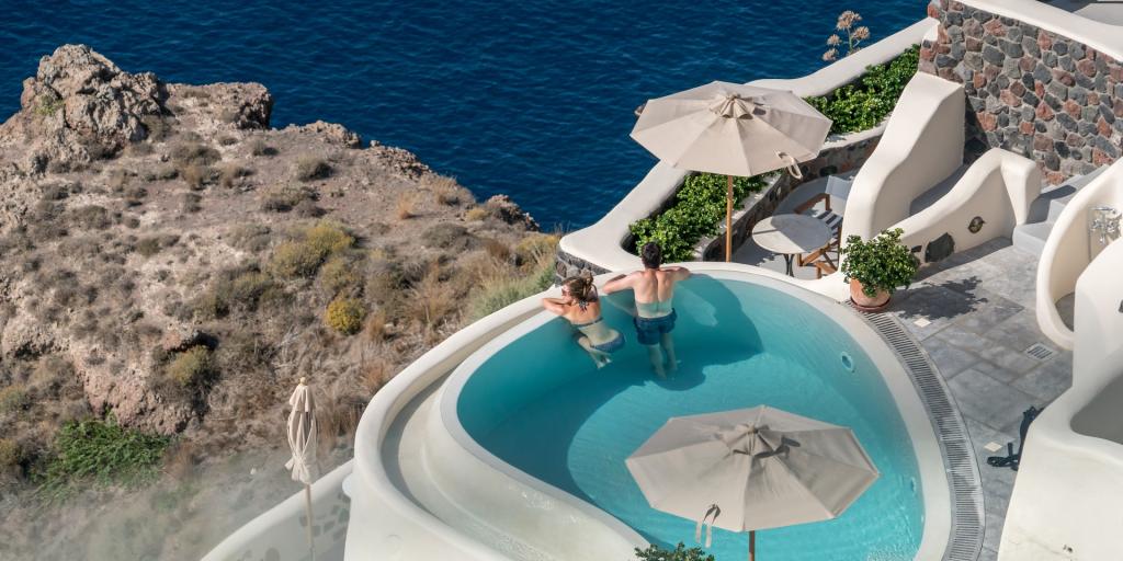 A couple look out at the views from their private terrace pool in Santorini, Greece