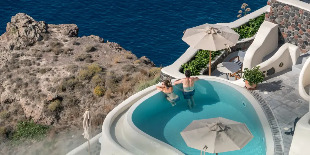 A couple look out at the views from their private terrace pool in Santorini, Greece