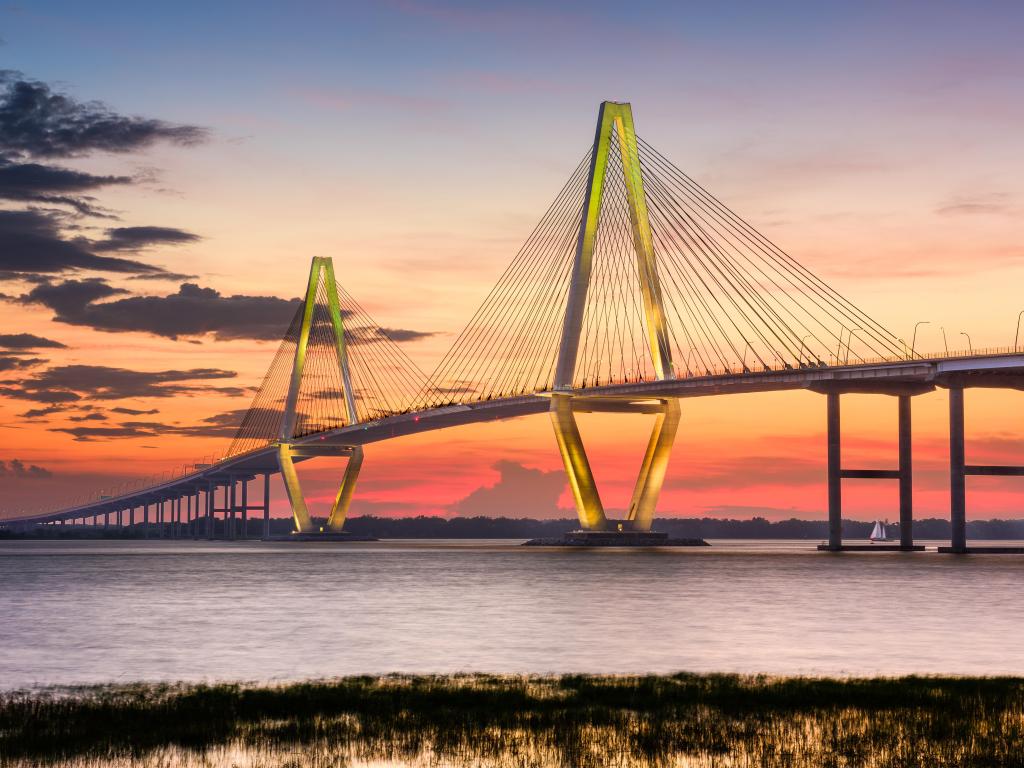 Bridge over wide river with pink sunset sky