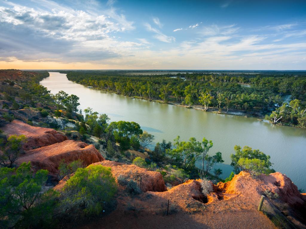 A view of the river from above, lined with trees and red rocks