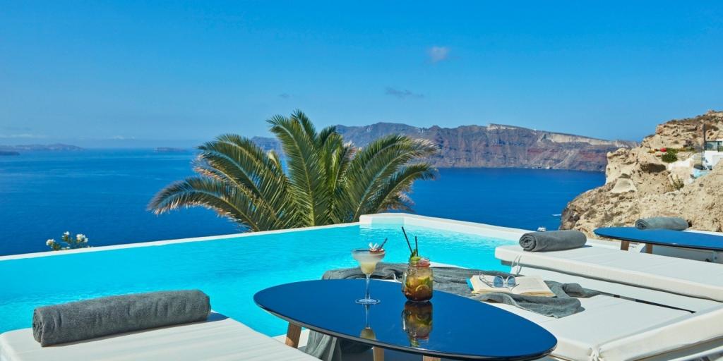 Two hotel loungers by a pool over looking the caldera in Santorini