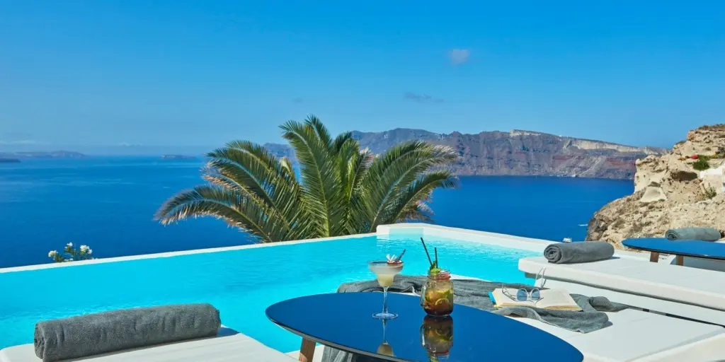 Two hotel loungers by a pool over looking the caldera in Santorini