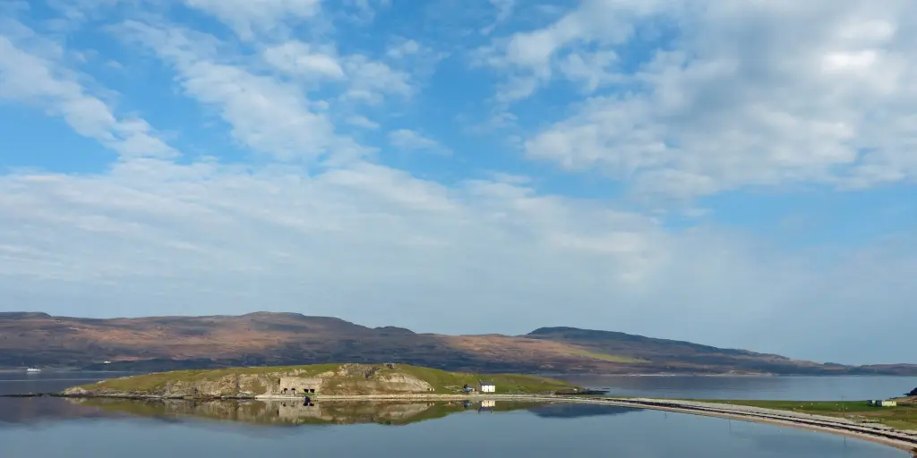 Square lime kilns on a promontory in Loch Eriboll, with the mountains in the background and blue skies
