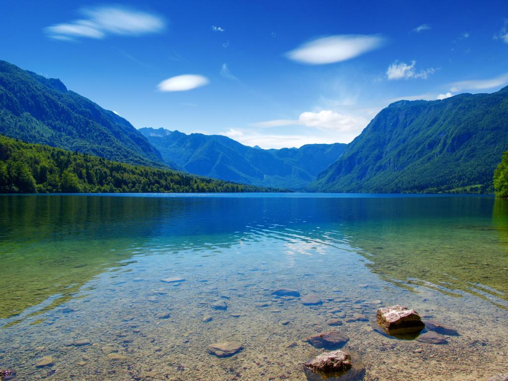 Golden Ears Provincial Park, BC, Canada with a tranquil lake in the foreground and mountains in the distance reflecting in the water on a clear sunny day.