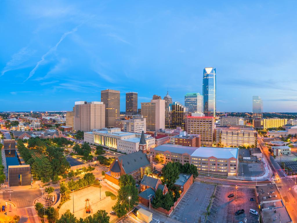 Oklahoma City, Oklahoma, USA with the downtown skyline at twilight and trees in the foreground.