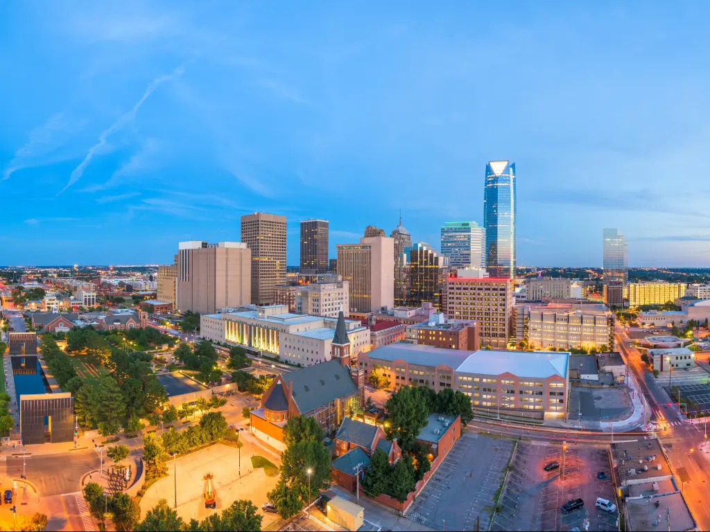 Oklahoma City, Oklahoma, USA with the downtown skyline at twilight and trees in the foreground.