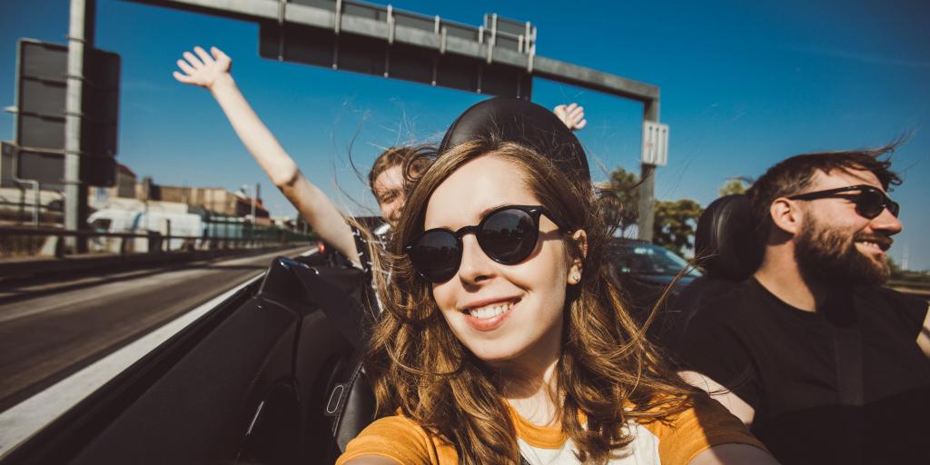 Happy group of friends taking selfie when road trip in convertible car on a sunny day