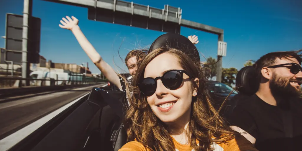 Happy group of friends taking selfie when road trip in convertible car on a sunny day