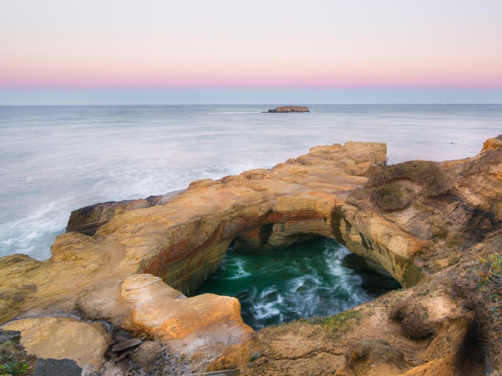 Devil's Punch Bowl, Devils Punch Bowl State Natural Area, Oregon, USA taken just before sunset with the stunning rock formation in the foreground and the sea in the distance.