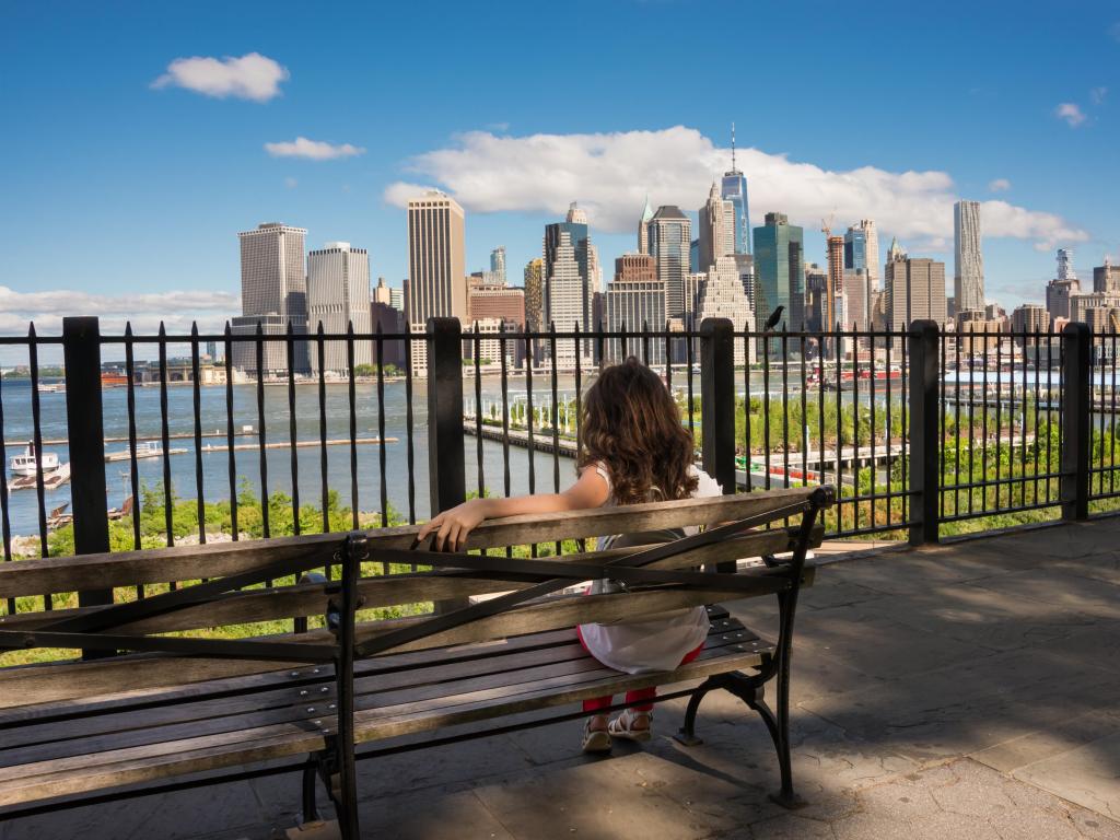 Woman sitting on Brooklyn Heights Promenade looking at the Manhattan Skyline