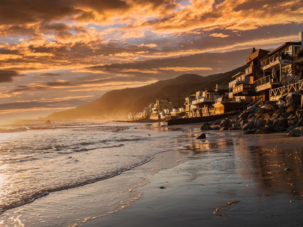 Beach at sunset with houses rising up the cliffs 