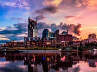 Nashville, TN, USA with the city skyline in the background and reflecting in the river in the foreground, taken at early evening with a dramatic sky.