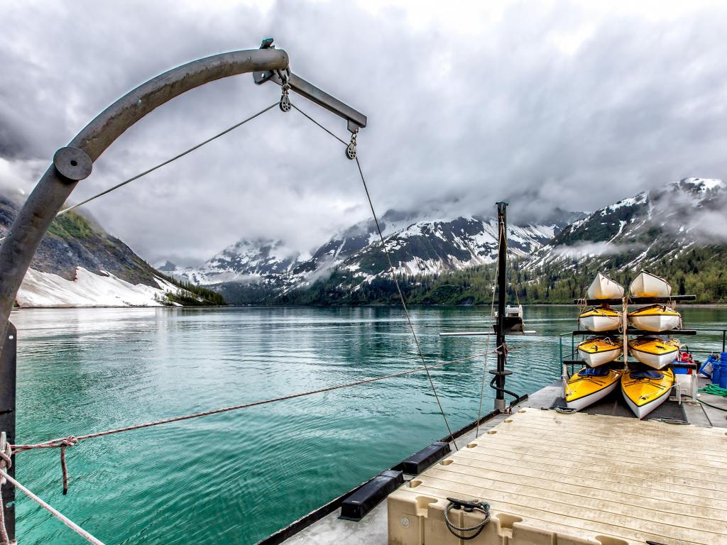 Yellow kayaks stacked on a small ship in Glacier Bay, Alaska, with mountains in the background