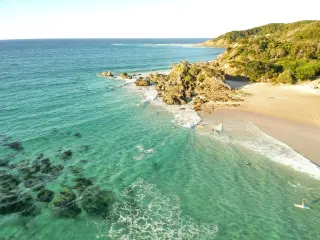Aerial image of the turquoise waters of Byron Bay on a bright day